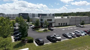 Parking lot view of Green Top Shooting Range with cars lined up in front of the gray building, American flag flying above the entrance.